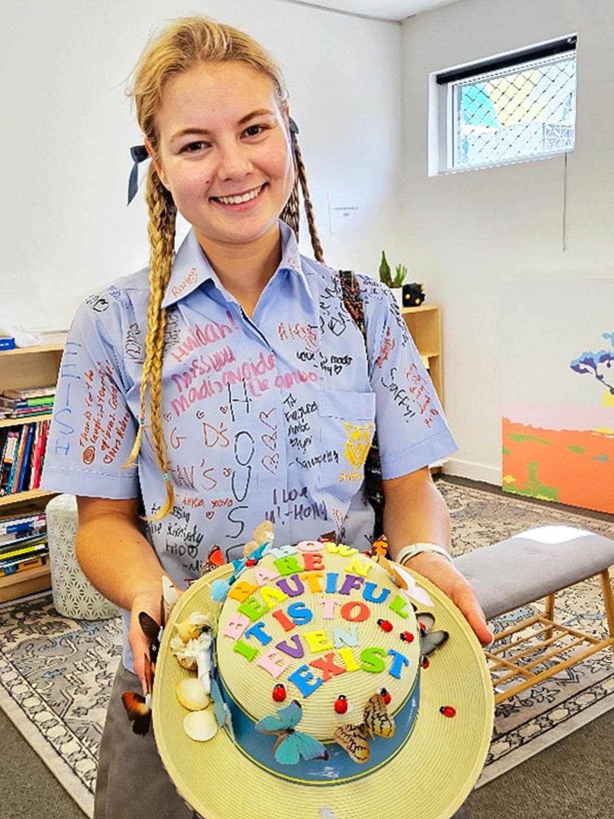 Academis student in a signed school shirt holding a decorated hat