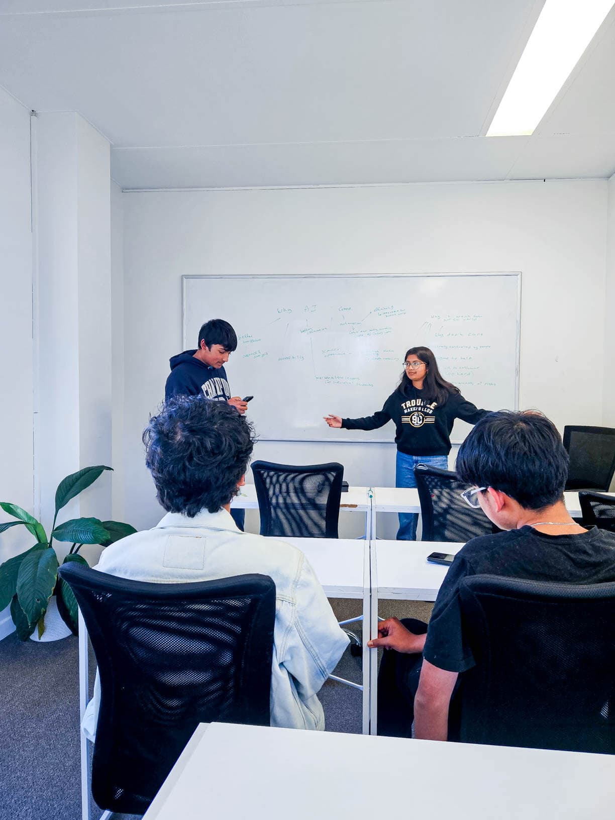 Students presenting at the whiteboard during an Academis class
